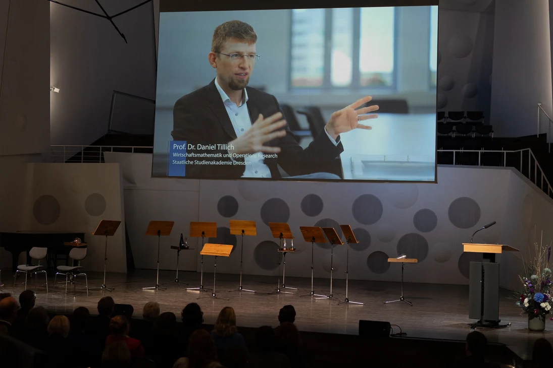 Prof. Dr. Daniel Tillich von der Studienakademie Dresden (Im Video auf dem Bildschirm) konnte zur Übergabe der Urkunde nicht persönlich anwesend sein.