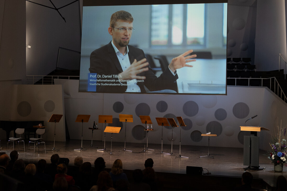 Prof. Dr. Daniel Tillich von der Studienakademie Dresden (Im Video auf dem Bildschirm) konnte zur Übergabe der Urkunde nicht persönlich anwesend sein. 